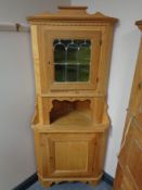 A blond oak double door corner cabinet