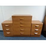 A five drawer chest together with a pair of three drawer bedside chests in a teak finish