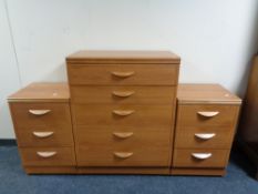 A five drawer chest together with a pair of three drawer bedside chests in a teak finish