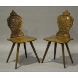 A pair of 20th century Continental stained beech hall chairs, each shield shaped back carved with