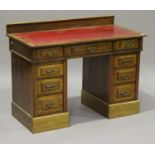 An Edwardian oak twin pedestal desk, the top inset with a gilt-tooled red leather writing surface