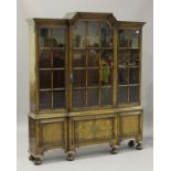 An early 20th century Queen Anne style walnut bookcase cabinet, the arched pediment above three