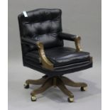 A modern buttoned black leather revolving office chair with studwork decoration, on outswept legs