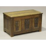 An early 20th century oak coffer, the hinged lid above a triple panel front carved with rosettes, on