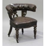 A William IV oak framed tub back library armchair, upholstered in brown leather, raised on turned