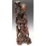 A large Chinese carved hardwood figure group of Shoulao and a boy acolyte, seated on the back of a