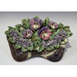 A pottery display of flowers in a brown glazed trough, probably French circa 1900, including pansies