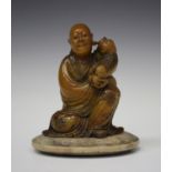 A Chinese carved soapstone figure group of a seated luohan and shishi puppy, probably 20th