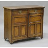 An Edwardian oak side cabinet, fitted with two drawers above panelled cupboards, raised on