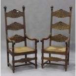 A pair of 20th century French stained beech ladder back armchairs with carved decoration, the drop-