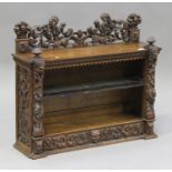 A late Victorian Continental oak dwarf bookcase with carved masks and foliate scrolls, the open