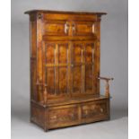 An 18th century provincial elm and ash bacon cupboard settle, the overhanging pediment above a