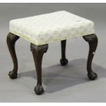 An early 20th century George III style mahogany footstool, the overstuffed seat raised on carved