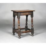 A late 17th century oak joint stool with a carved foliate frieze, on turned and block legs, height