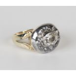 A gold, silver and diamond ring, collet set with an oval cut diamond within a surround of eleven