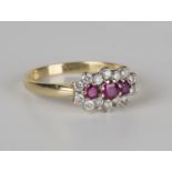 An 18ct gold, ruby and diamond ring, mounted with three circular cut rubies within a surround of