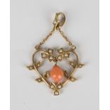 A gold, coral and seed pearl pendant, circa 1910, in a heart shaped floral and foliate openwork