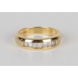 An 18ct gold and diamond ring, mounted with a row of seven princess cut diamonds, ring size approx