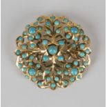 A gold and turquoise brooch of shaped circular form with floral and foliate pierced decoration,