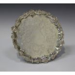 A Victorian silver circular salver with engraved centre and cast scroll rim, on three scroll feet,