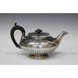 A George IV silver teapot of half-reeded squat circular form, engraved with an armorial, London 1823