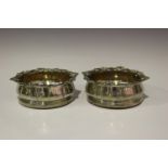 A pair of George IV silver circular wine coasters, each rim cast with stylized leaves and scrolls
