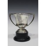 A George V silver trophy cup, the urn shaped body flanked by two angular handles, on a stepped foot,