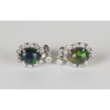 A pair of white gold, black opal and diamond pendant earrings, each oval black opal within a