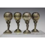 A set of four George V silver novelty pepperettes, each formed as a putto holding a ball above its