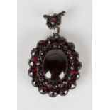 A Victorian Bohemian garnet oval pendant locket, the oval cabochon garnet within a two row