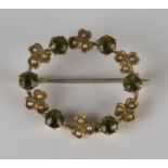 A gold, seed pearl and peridot oval brooch, circa 1910, claw set with six circular cut peridots