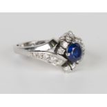 A white gold, sapphire and diamond ring in a twist design, claw set with a circular cut sapphire