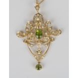 A 15ct gold, peridot and seed pearl pendant, circa 1910, in a scroll pierced and foliate design,