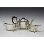 A George V silver three-piece tea set of oval form with shaped rims, raised on scroll legs,