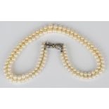 A three row necklace of graduated cultured pearls on a white gold and sapphire clasp, designed as