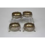 A harlequin set of four Victorian silver circular salts, each embossed and engraved with foliage,