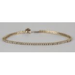 A gold and diamond bracelet, claw set with a row of circular cut diamonds within square shaped