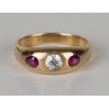 A gold, diamond and ruby three stone ring, gypsy set with a cushion cut diamond between two gypsy