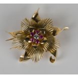 A French gold, ruby and diamond brooch in a stylized floral design, claw set with a circular cut