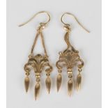 A pair of gold pendant earrings, each mounted with three graduated drops beneath a scrolling