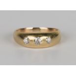 A gold and diamond three stone ring, gypsy set with a row of cushion cut diamonds, ring size