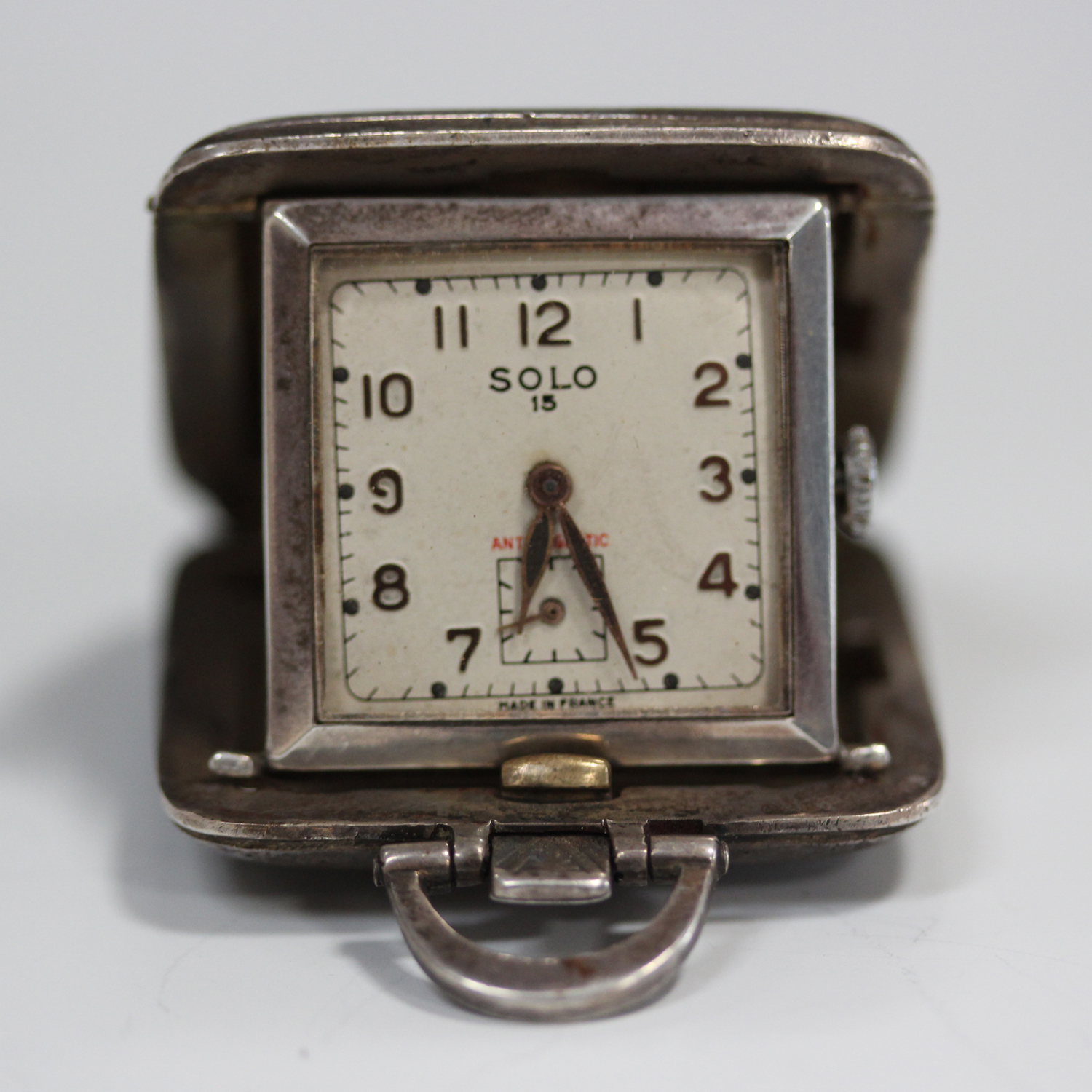 A Solo 15 silver square cased travelling watch, the signed silvered dial with gilt Arabic numerals