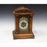 An early 20th century walnut mantel clock with eight day movement chiming on gongs, the backplate