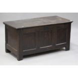 An 18th century oak coffer, the hinged lid revealing a candle box above a triple panel front, on