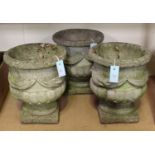A set of three 20th century cast composition stone garden urns, the half-reeded bodies with swag