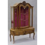 A 20th century French oak vitrine with carved scroll decoration, the arched top fitted with a single