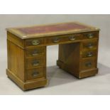 A late Victorian oak twin pedestal desk, the moulded top inset with a gilt-tooled red leather