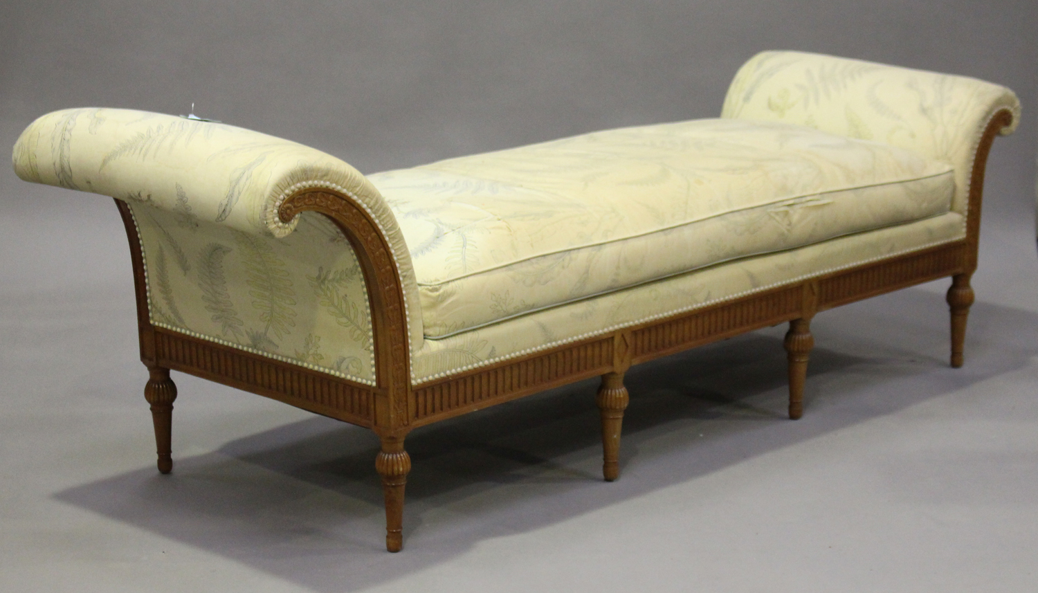 A 20th century Louis XVI style walnut day bed with carved decoration, upholstered in floral