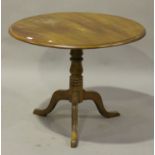 An early 20th century walnut circular tip-top wine table, raised on a turned column and tripod