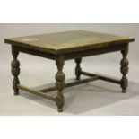 A George V oak drawleaf dining table with reeded baluster and block legs united by an 'H' stretcher,